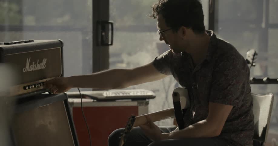 A man turns the knob on his amplifier