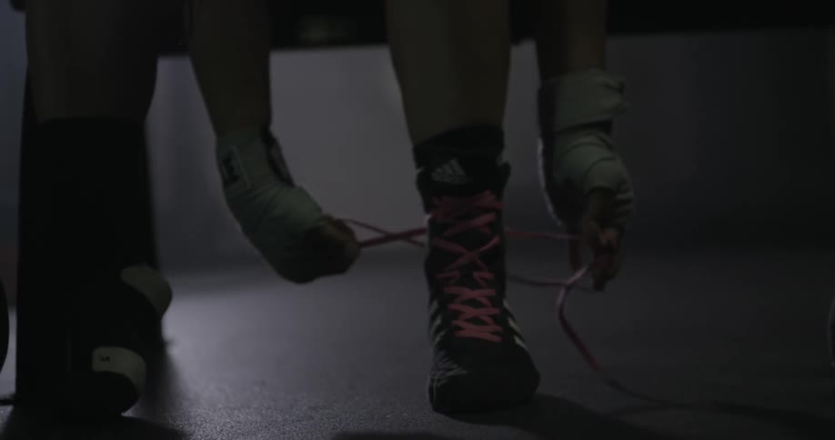 A person wearing gloves ties their shoe