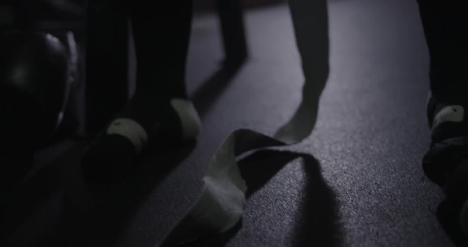 Athletic tapes is draped on the floor between a person's legs