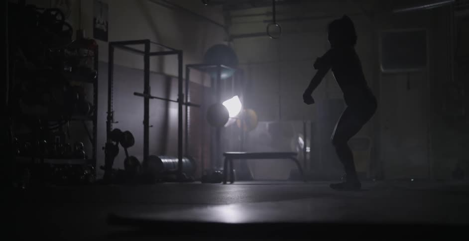 A woman jumps around dancing to warm up in a gym