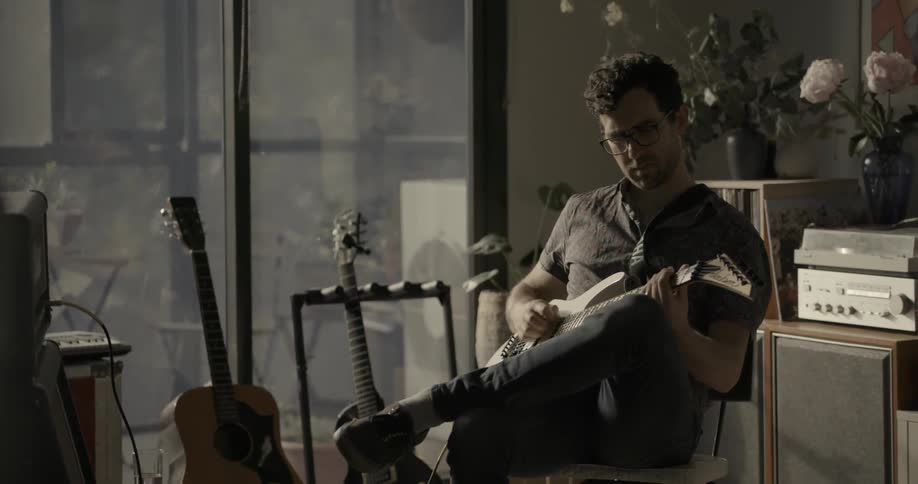 A guitarist sits and plays on his guitar