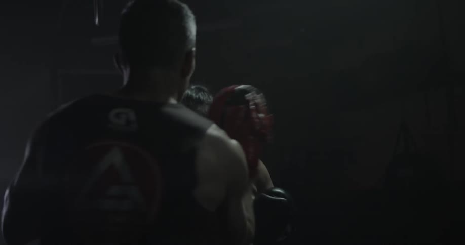 Man and woman practice boxing in a dimly lit gym