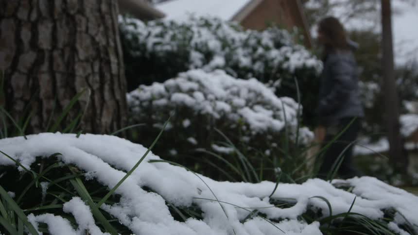 A woman walks in the yard filled with snow
