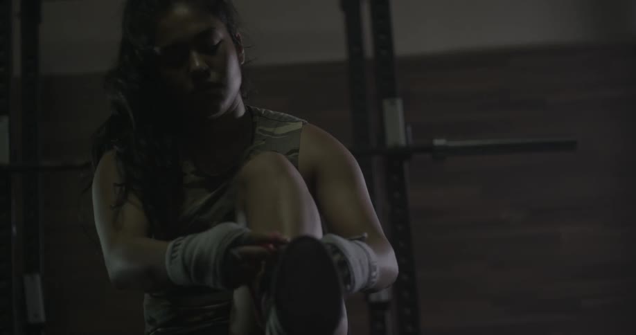 A woman is tying her boots to being a workout