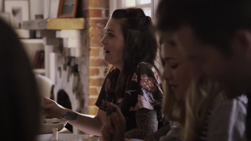 A group of people converse and laugh while eating a meal