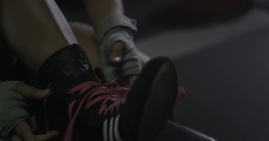 A woman is tying her boots on