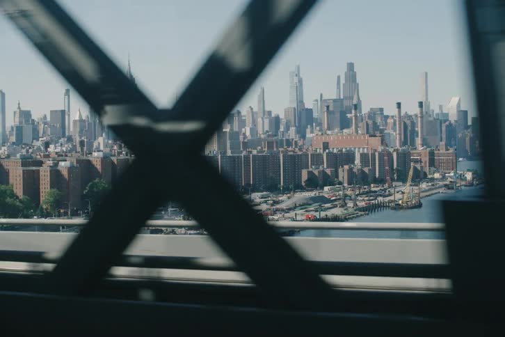A dynamic point-of-view shot of the New York City skyline while driving across a bridge on a sunny day