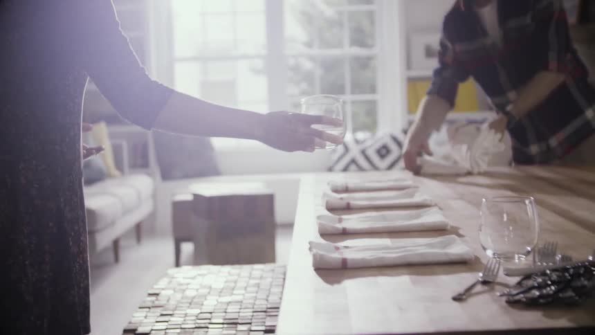 A woman and man are setting a table