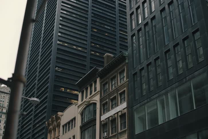 A cinematic slow pan from behind a traffic light reveals a mix of modern and classic architecture on a city street