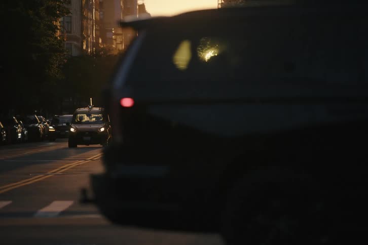 Cinematic slow-motion shot of a New York City street at sunset with traffic and cyclists silhouetted by the golden light