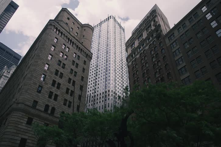 A slow dolly shot reveals modern and historic skyscrapers from a low angle in a dense urban city