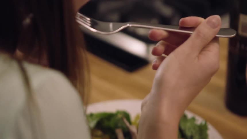 A woman takes a bite of some meat from a plate