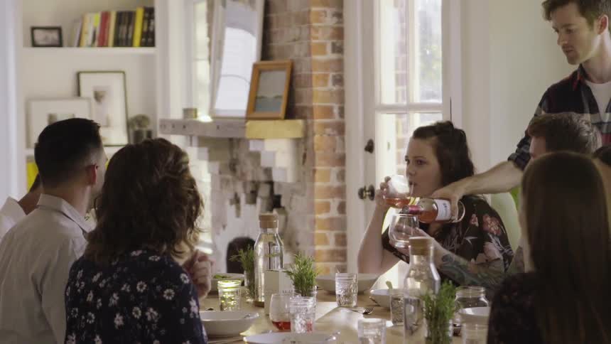A man pours drinks for a family dinner