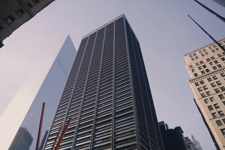 A smooth dolly shot reveals the towering skyscrapers of downtown New York City from underneath sidewalk scaffolding