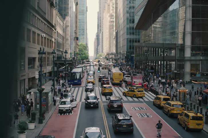 A high-angle slow zoom-out captures the bustling traffic and crowds of people on a busy street in Midtown Manhattan, New York City