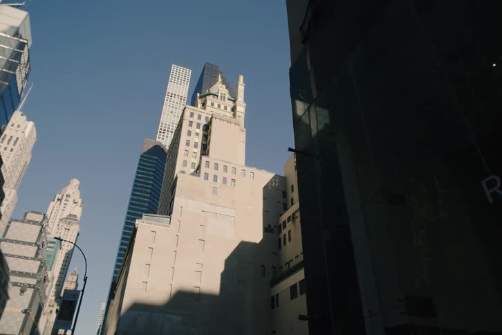 A slow, low-angle pullback reveals towering Manhattan skyscrapers against a clear blue sky