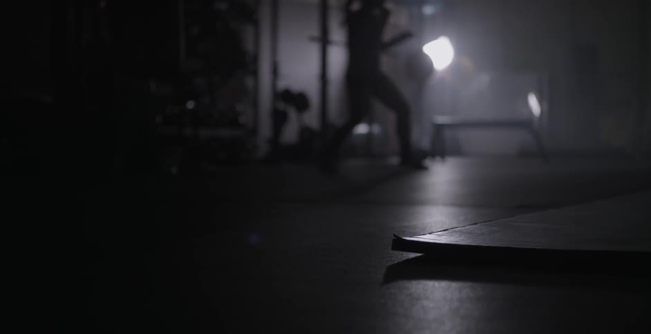 Woman shadowboxing in a dark area indoors