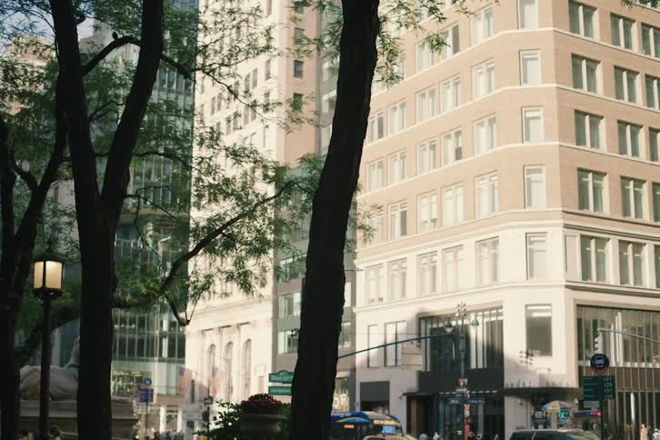 A slow pan across a New York City street corner reveals a classic street light and the iconic lion statue in front of the Public Library