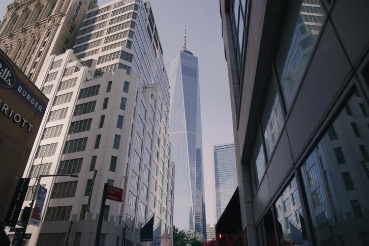The camera slowly reveals the One World Trade Center from a low angle on a city street in New York City