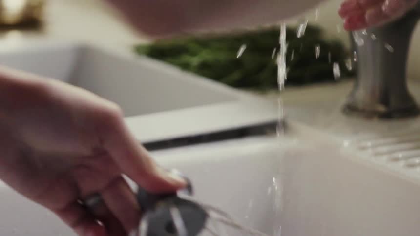 A person is washing a whisk in the sink