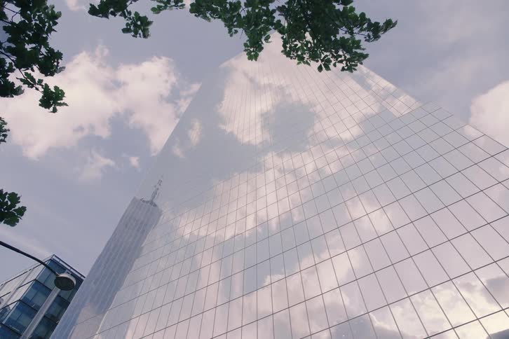 A low-angle dolly shot reveals the reflective glass facade of a modern skyscraper near the 9/11 Memorial in New York City