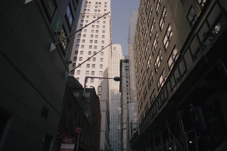 A slow dolly shot moves through a narrow street canyon surrounded by towering skyscrapers in a dense urban city