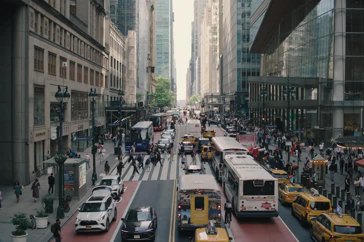 An elevated slow zoom-out reveals the bustling crowds of pedestrians and heavy traffic on a busy street in New York City