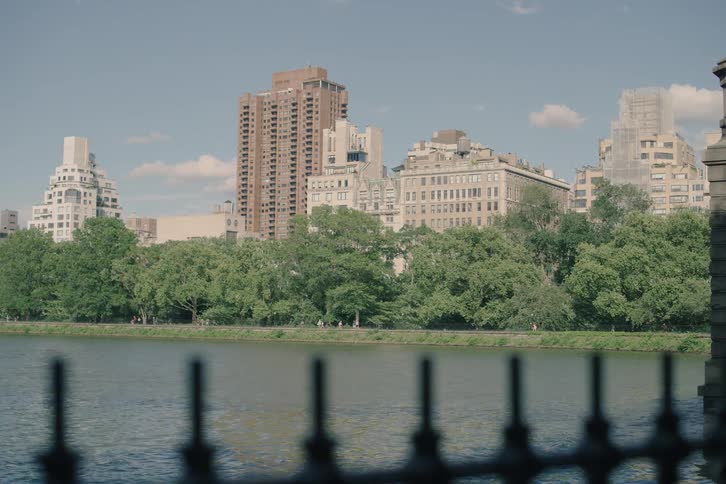 A scenic view of the Upper East Side skyline across the Jacqueline Kennedy Onassis Reservoir in Central Park on a sunny day
