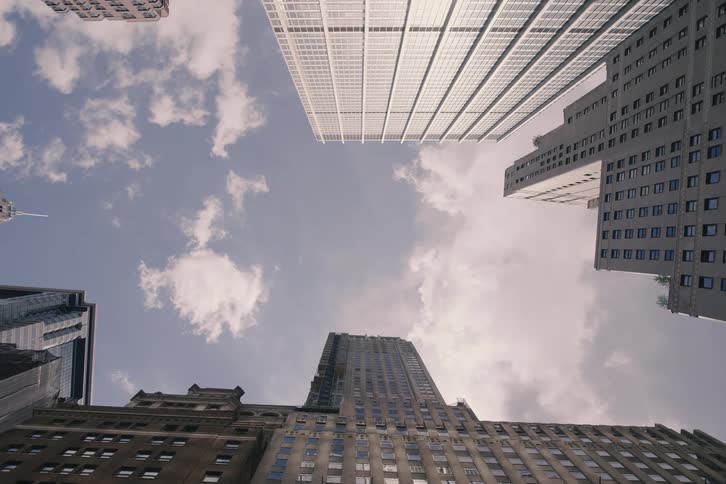 Urban timelapse captures clouds drifting above towering skyscrapers from a low-angle perspective