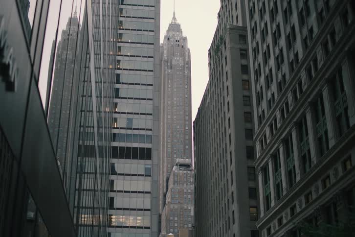 Looking up from a city street, the camera slowly tilts to reveal a classic art deco skyscraper between modern high-rises