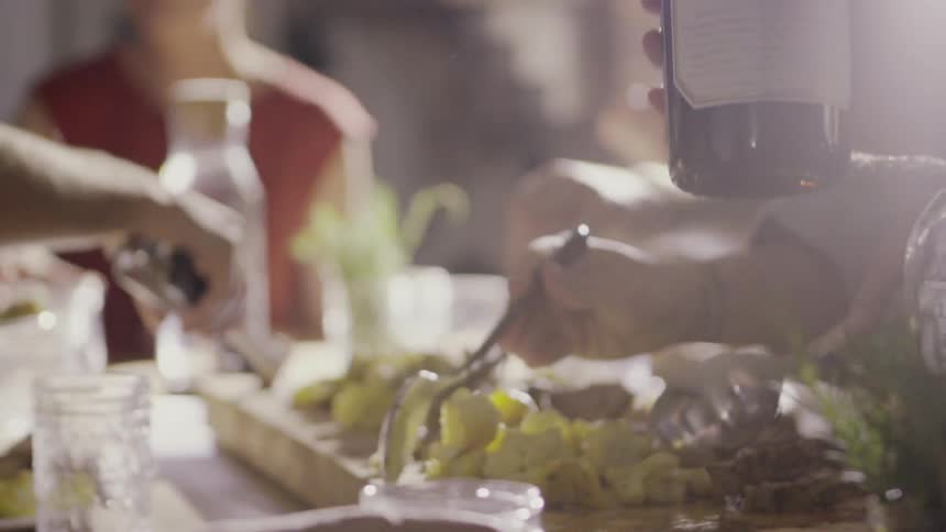 People serve themselves from a platter of food set on a dinner table