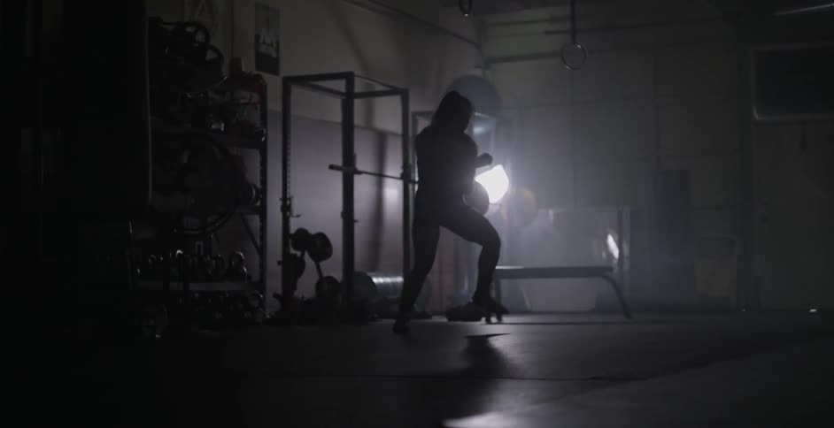 A female athlete is shadow boxing in a gym