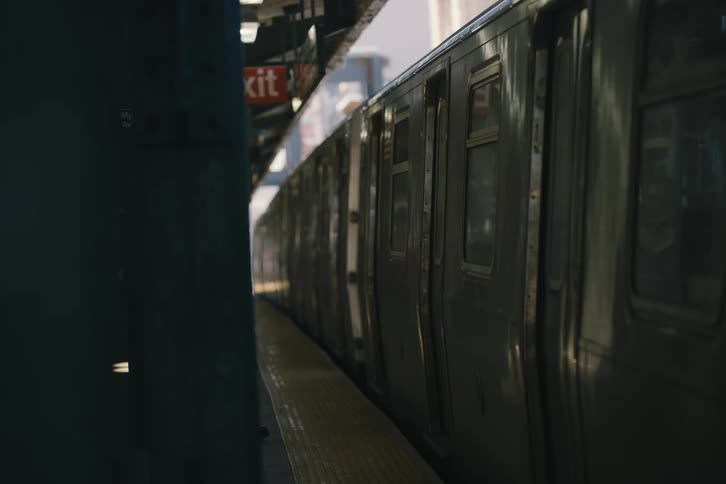 A subway train slowly pulls away from an elevated station platform in the city