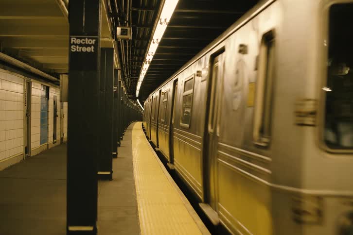The W train emerges from a dark tunnel and pulls into the dimly lit Rector Street subway station in New York City