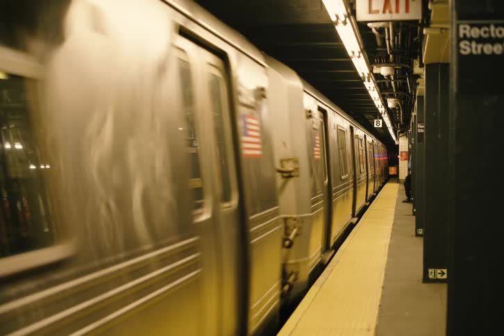 A New York City subway train departs the Rector Street station and disappears into the dark tunnel