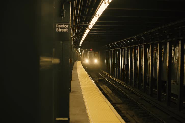 Cinematic reveal of a subway train arriving at a dark, underground station platform in New York City
