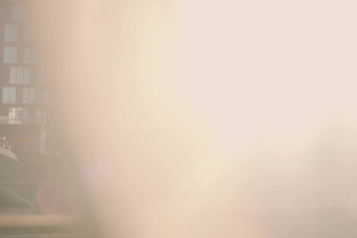 A cinematic point-of-view shot from a moving subway train reveals the gritty New York City skyline basked in a beautiful, hazy sun flare