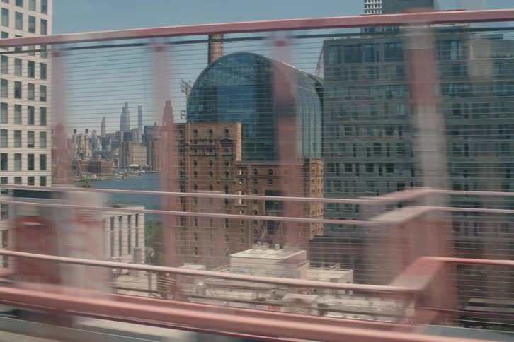 A dynamic tracking shot from a train crossing a bridge, revealing the diverse architecture and skyline of a bustling city on a sunny day