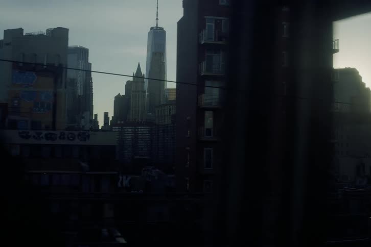 A cinematic slow-motion tracking shot reveals the Manhattan skyline at sunrise, framed by the silhouetted structure of a moving train on a bridge