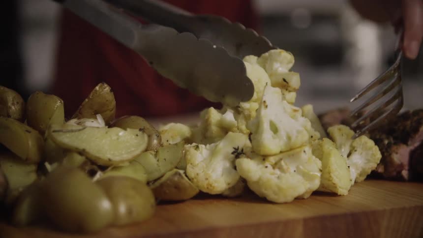 Vegetables are placed on a board with tongs