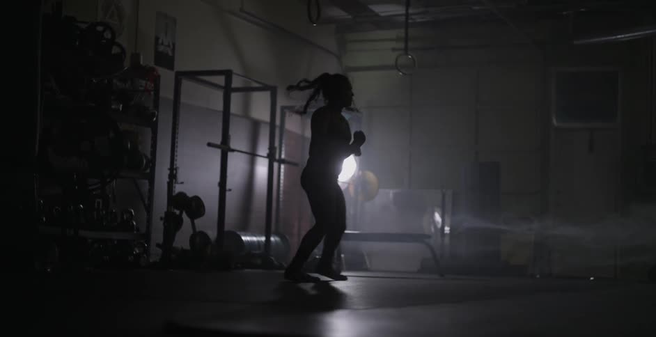 A female athlete is practicing footwork and shadow boxing in a gym