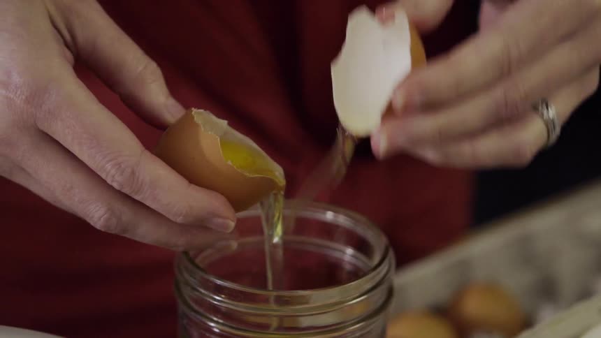 Woman sifts an egg white from a yolk