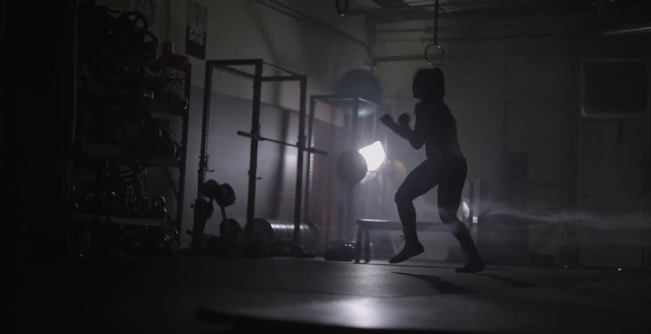 A female athlete is practicing footwork and shadow boxing in a gym
