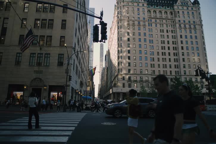 A slow cinematic pan across a busy intersection on 5th Avenue in New York City with pedestrians and traffic in motion