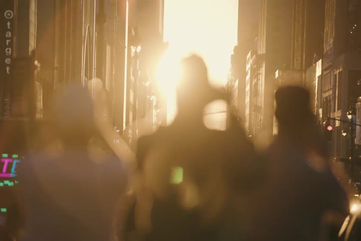 Three friends are silhouetted against a brilliant golden sunset as they take photos on a busy city street