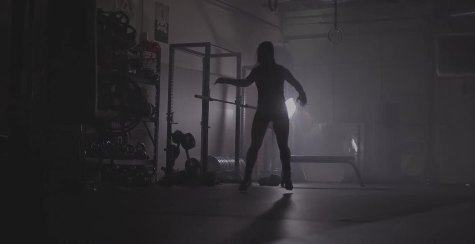 A woman jumps back and forth exercising in a gym