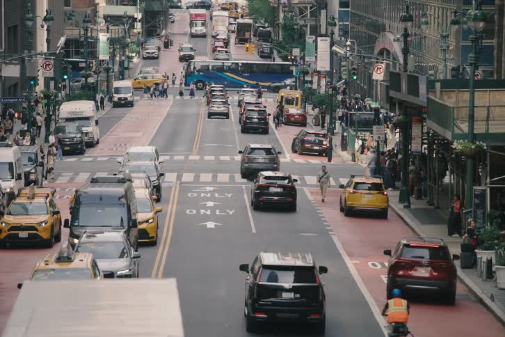 High-angle telephoto shot slowly zooms out on a busy New York City street with heavy traffic and pedestrians on the sidewalks