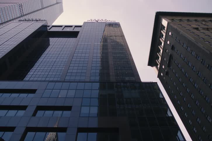 A slow pan reveals a modern glass skyscraper next to a classic building from a low-angle perspective