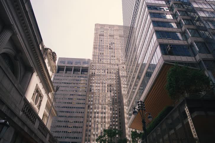 A slow cinematic push-in shot looking up at the towering skyscrapers from a bustling street in New York City