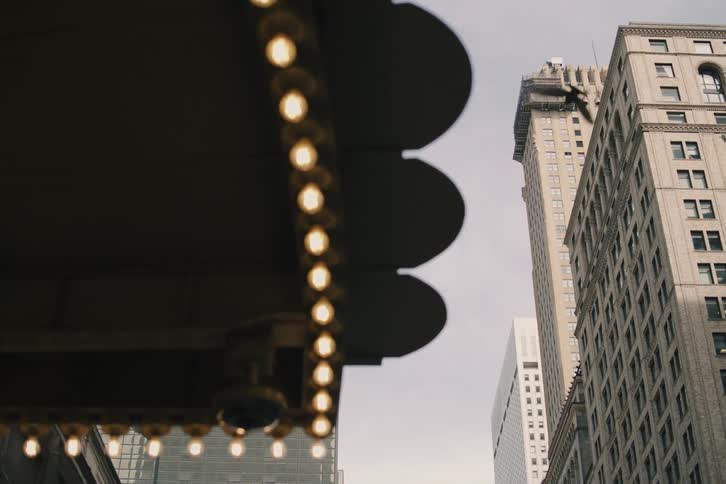 A cinematic low-angle shot of New York City's Chrysler Building with pigeons flying by and a slow focus pull to a classic lit awning